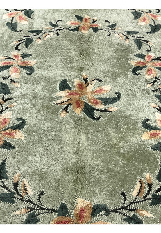Center detail of hand-hooked rug with a peach and rose flower spray on a celadon green ground