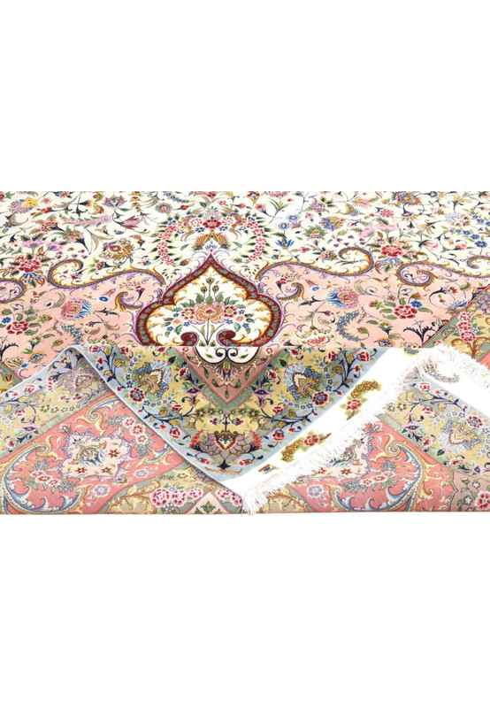 Folded corner of wool and silk Tabriz rug revealing the intricate floral border and ivory selvage