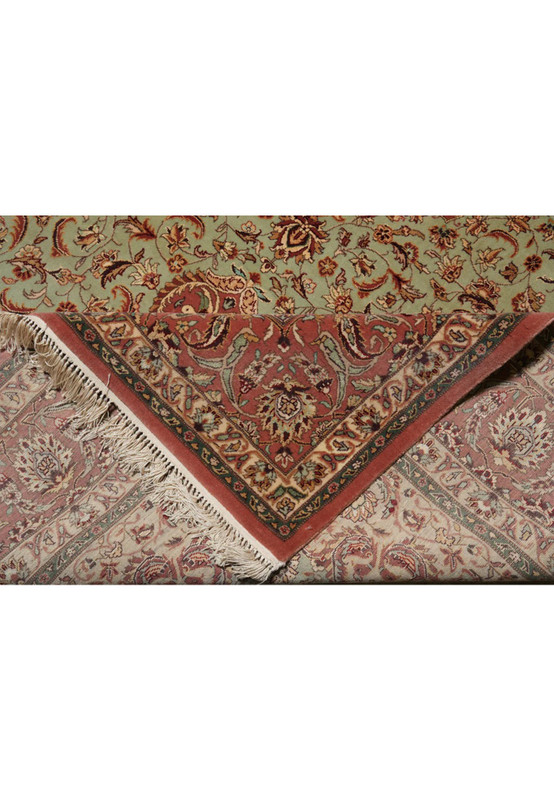 Folded edge of Persian Isfahan rug showing terracotta border and ivory floral guard stripe