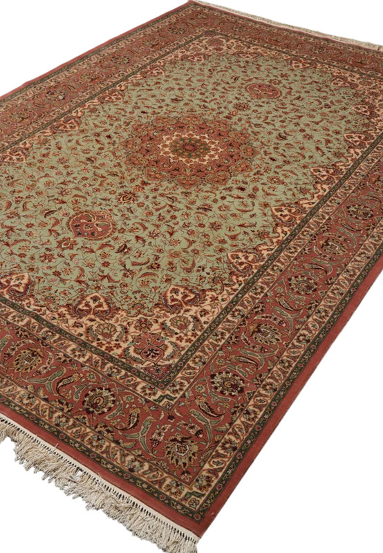 Angled view of Persian Isfahan rug, sage field and rose medallion framed by terracotta border