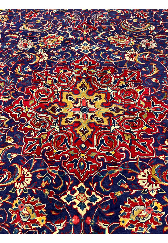 Center detail of navy Mahal rug showing gold and rose star accent surrounded by red palmettes