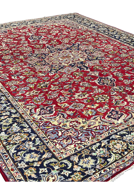 Angled view of large Persian Najafabad wool rug, red and navy floral design ideal for formal living or dining room