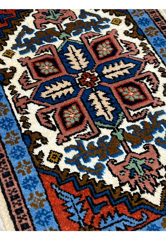Angled view of small Persian Ardebil wool and silk rug, vivid sky blue border with brown floral motifs