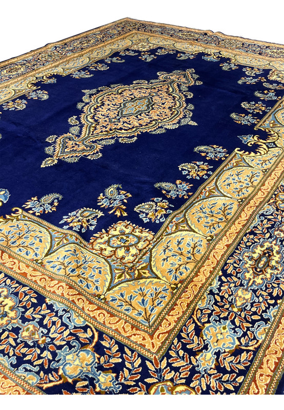 Angled corner view of 9'10 x 13'7 Persian Yazd rug, navy field with floral spandrel and ivory scalloped border