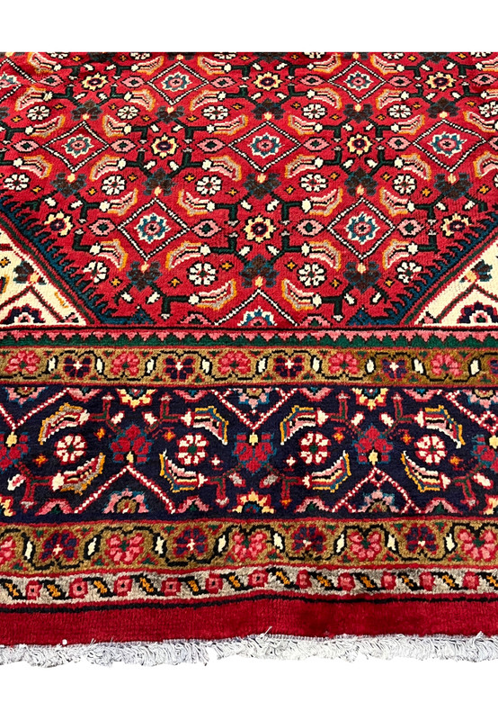 Lower border closeup with red field, navy floral vine guard and caramel minor stripe near the fringe