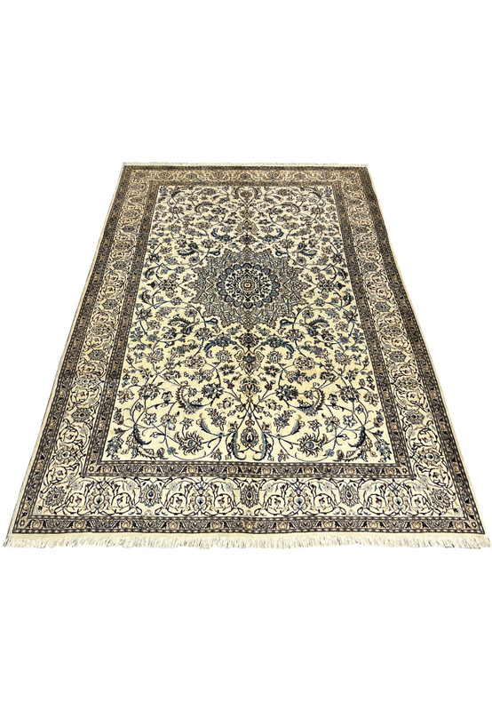 Full ivory Nain rug shown at an angle with blue medallion, vine scroll field and floral borders