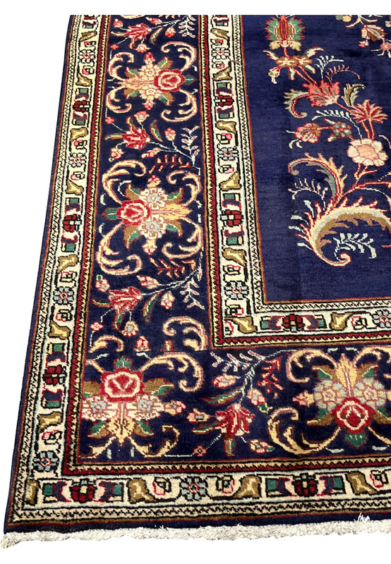 Navy main border of scrolling acanthus and rose palmettes framing a floral corner of the rug