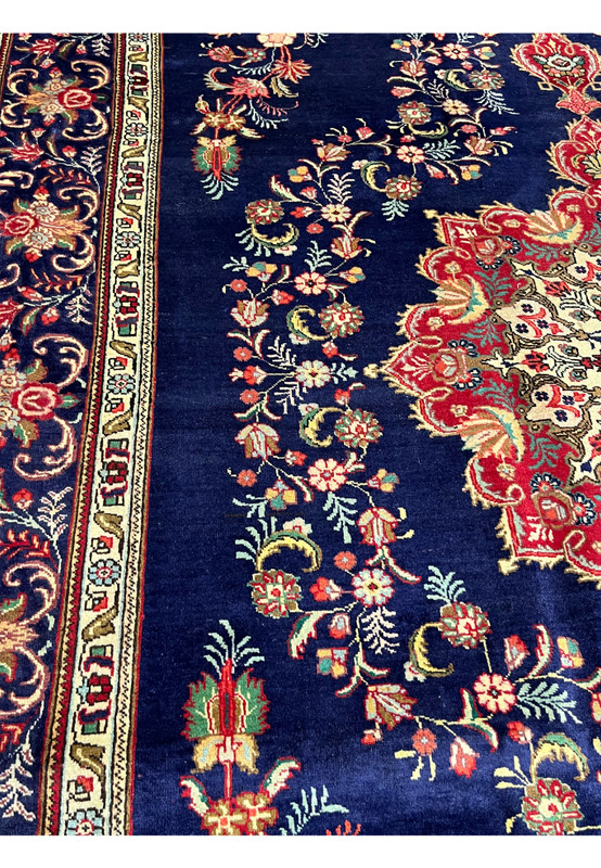 Close view of the wool pile showing red, gold, teal and ivory florals on a deep navy ground