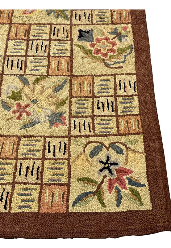 Corner of the hand-hooked rug from India with rosette flower and earth tone tiles