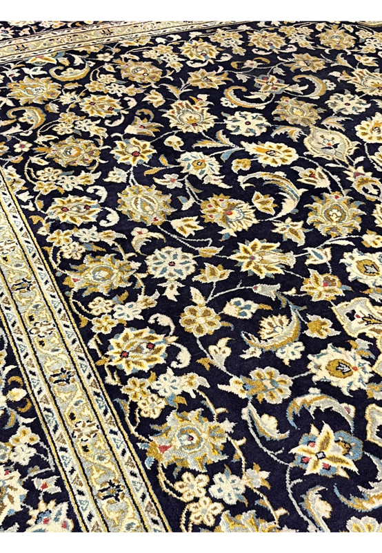 Detailed look at the densely knotted floral drawing in antique gold powder blue and ivory