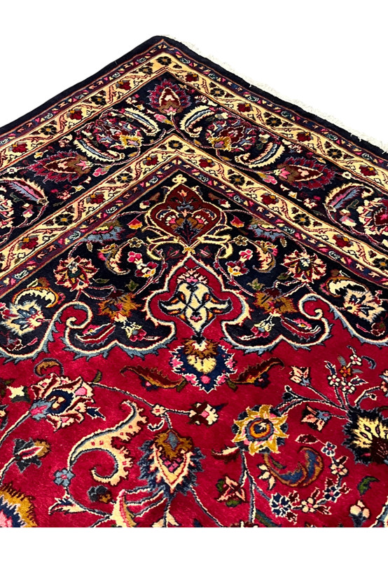 Inner border detail with charcoal pendant palmettes meeting the rich red Mashad field