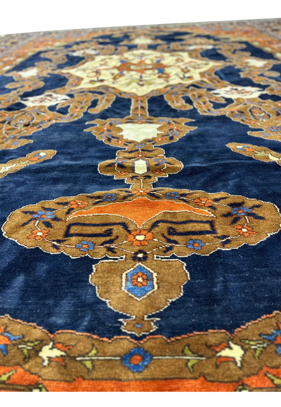 Detail of the finely knotted wool pile showing orange leaf motifs on the navy ground