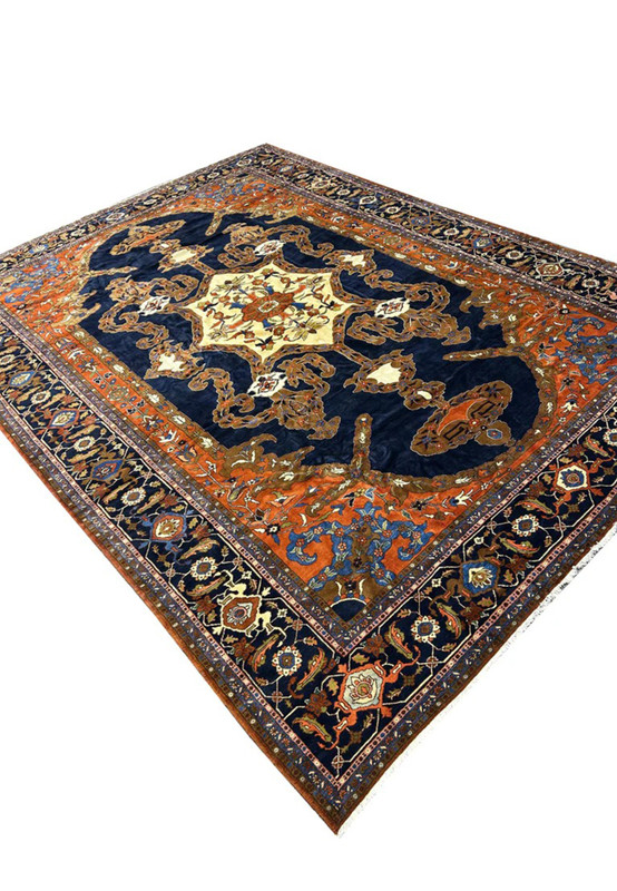 Angled view of the 14x19 palace size Heriz showing navy field rust spandrels and camel arabesques
