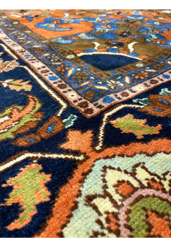 Closeup of rust border and navy field meeting with scrolling vines and ivory guard band