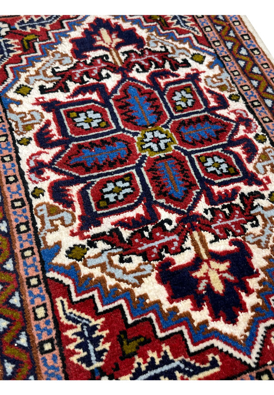 Angled view of the wool and silk Ardebil rug showing pile sheen across the red field