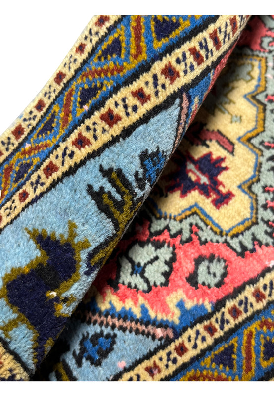 Rolled corner revealing dense hand-knotted wool and silk pile and the vivid powder blue and coral palette