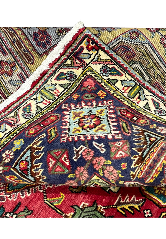 Folded edge showing the navy border, ivory selvage, and the hand-knotted back of the Tabriz