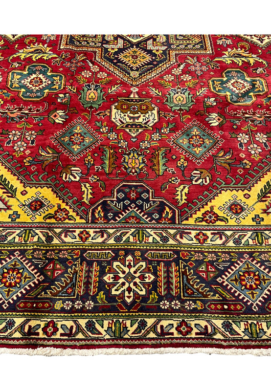 Lower field detail of the Tabriz with diamond medallions, floral sprays, and a small fountain motif on red