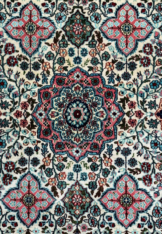 Close-up of the central medallion of a 3 x 5 Persian Qum Silk Rug, featuring detailed patterns in deep blue, red, and pink.