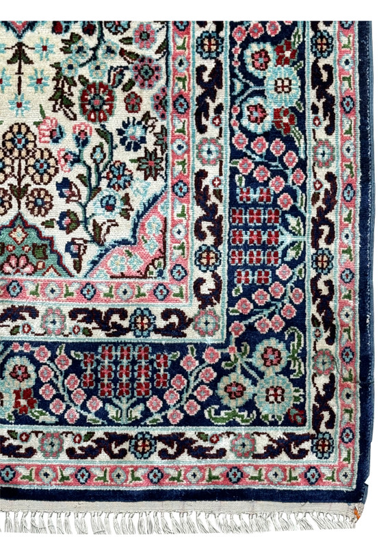 Close-up of the intricate border of a 3 x 5 Persian Qum Silk Rug, featuring floral and geometric patterns in navy and pink.