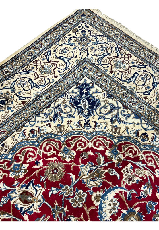 Inner border detail of Persian Nain rug with repeating floral motifs, navy outlines, and precise hand knotted structure