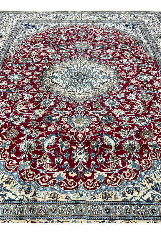 Midfield detail of red Persian Nain rug with dense floral vines, silk highlights, and precise hand knotted pattern