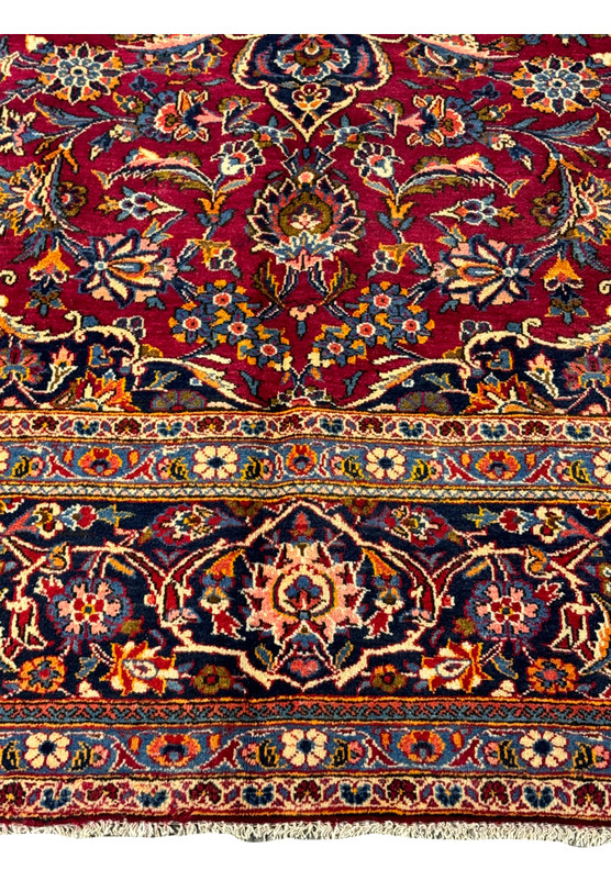 Corner detail of the Persian Kashan rug, where the opulent border meets the vibrant, patterned field.