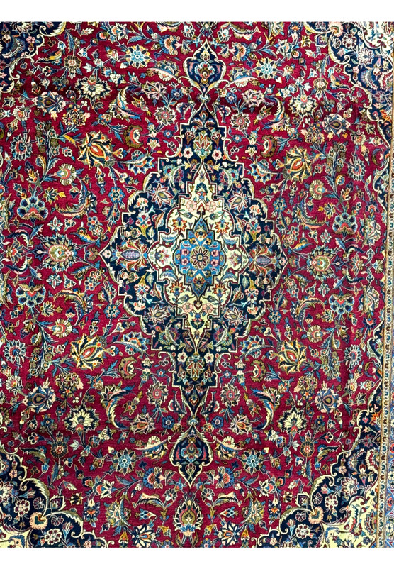 Close-up of the intricate and colorful floral designs against the burgundy background of a Persian Kashan rug