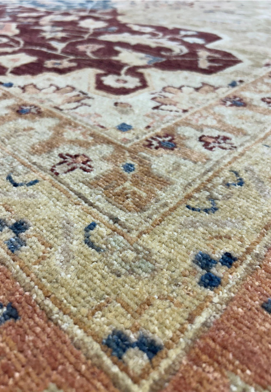 Close-up of the Agra rug's surface, focusing on the intricate floral patterns and vibrant colors. The texture of the natural wool fibers is clearly visible, highlighting the rug's durability and elegance.