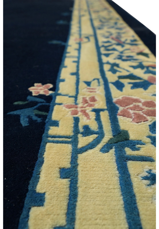 Close-up of ivory border with floral motifs on navy blue Beijing Art Deco rug.