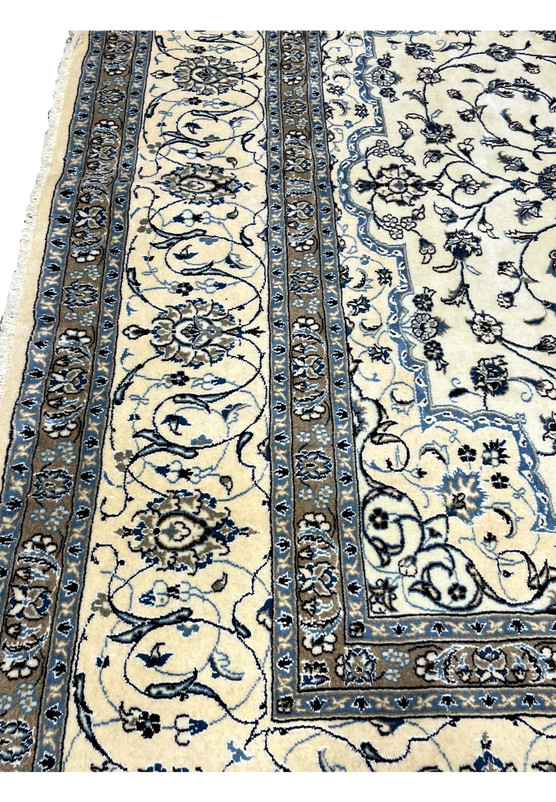Beige and blue border section of 10x13 Persian Nain 9LA Rug featuring floral motifs outlined in navy and silk highlights.