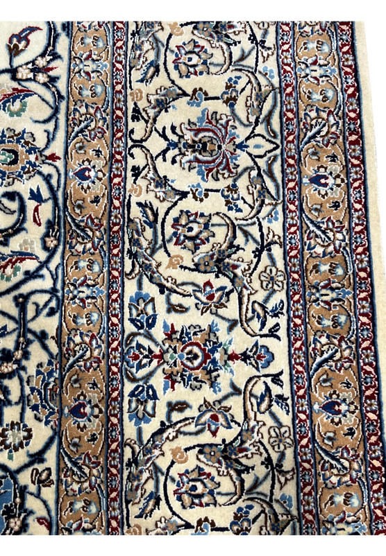 Zoomed border detail of Persian Nain 4 LA Habibian rug featuring floral scrolls in beige, navy, and blue framed by fine silk lines and tight weave.