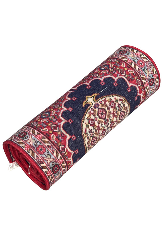Persian Bijar runner rolled up, showing navy scalloped medallion on deep red field with ivory and pink floral borders.