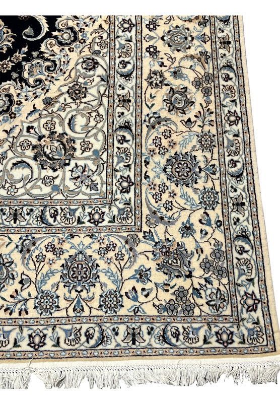 Border close-up of a Persian Nain Habibian rug showing intricate floral bands with ivory ground, pale blue blossoms, and fine navy outlining