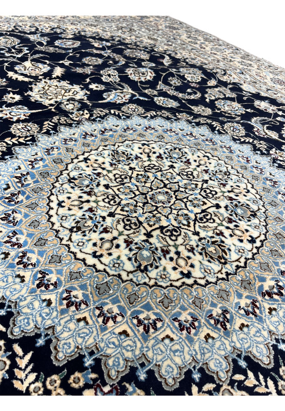 Detailed view of the central medallion of a Persian Nain 6LA Habibian rug with layered floral geometry in ivory, light blue, and soft brown tones