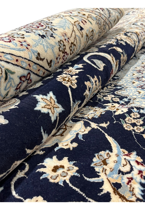 Close-up of a rolled Persian Nain Habibian rug highlighting dense knot structure, smooth wool surface, and sharp floral detailing