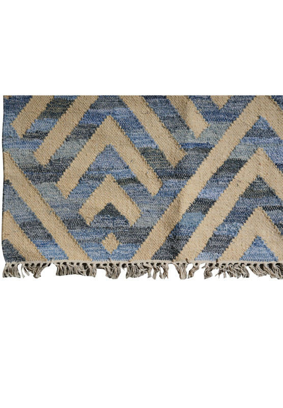 Corner detail with cotton fringe and the zigzag chevron border meeting the cream field along the rug edge