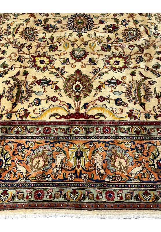 Top center detail of the Tabriz showing palmettes saz leaves and the animal figure border with stylized hares and deer