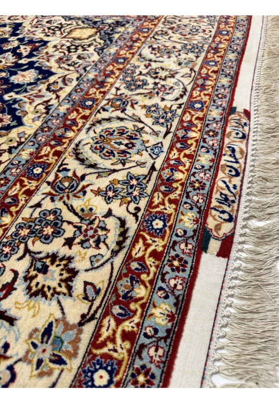 Lower border detail with palmettes, sage green leafwork, and the ivory cornerpiece geometry meeting the navy field at the corner of the rug