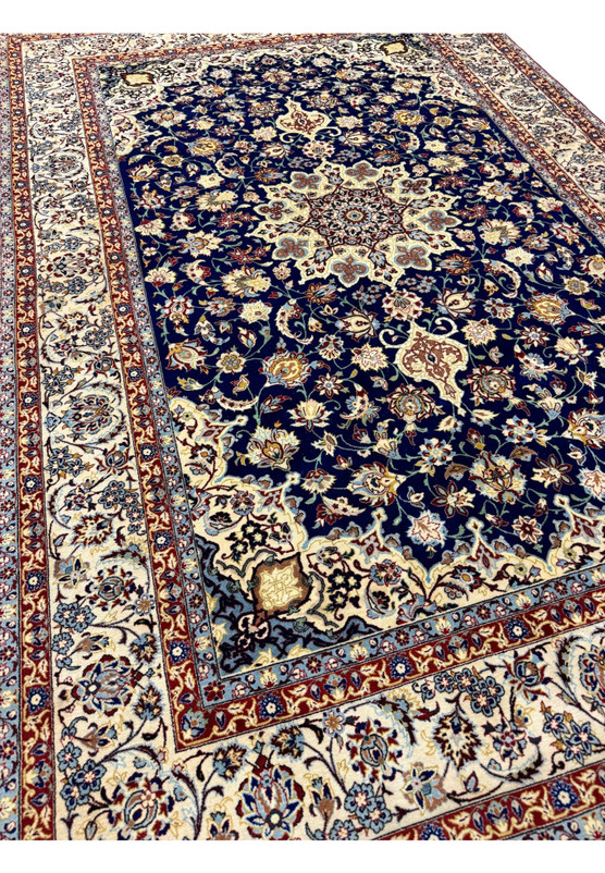 Angled three-quarter perspective of the Persian Isfahan revealing scale, the depth of the royal blue field, and the silk highlights catching the light