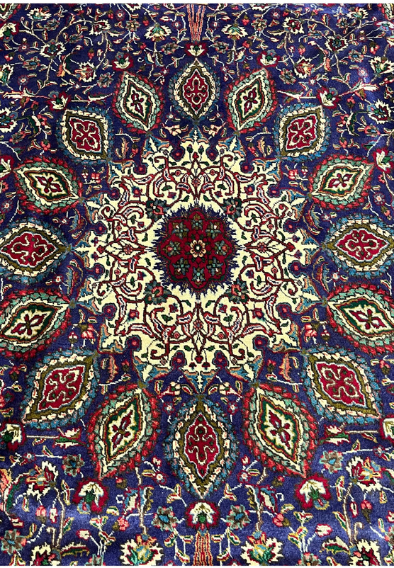 Close-up of ivory gonbad medallion on Persian Tabriz rug showing radiating cartouche rings around central rosette
