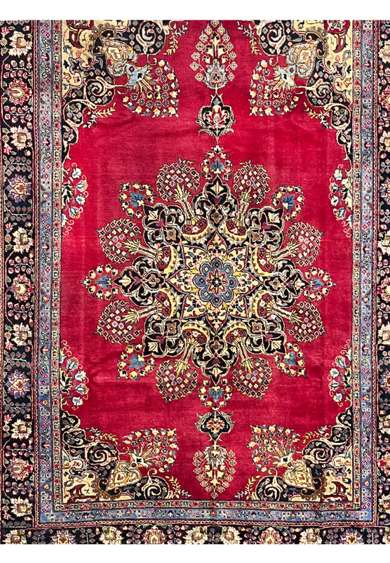 Closeup of Persian Kerman midfield showing the lobed sunburst medallion radiating into bouquet sprays on deep red ground