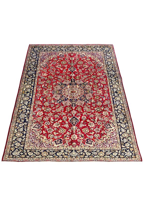 Persian Isfahan rug laid down on floor showing full composition with dense allover palmette and saz leaf design on deep red ground