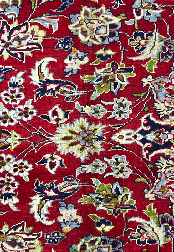 Closeup of Persian Isfahan field motifs and patterns showing palmette heads, saz leaves, and scrolling vines woven on crimson ground