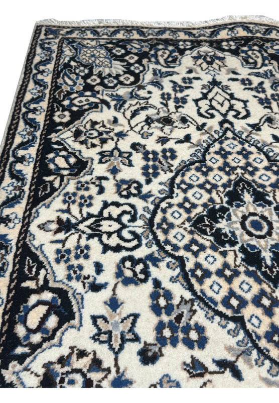 Upper corner detail of authentic Persian Nain rug, ivory minor border with rosette vine framing the navy floral main border