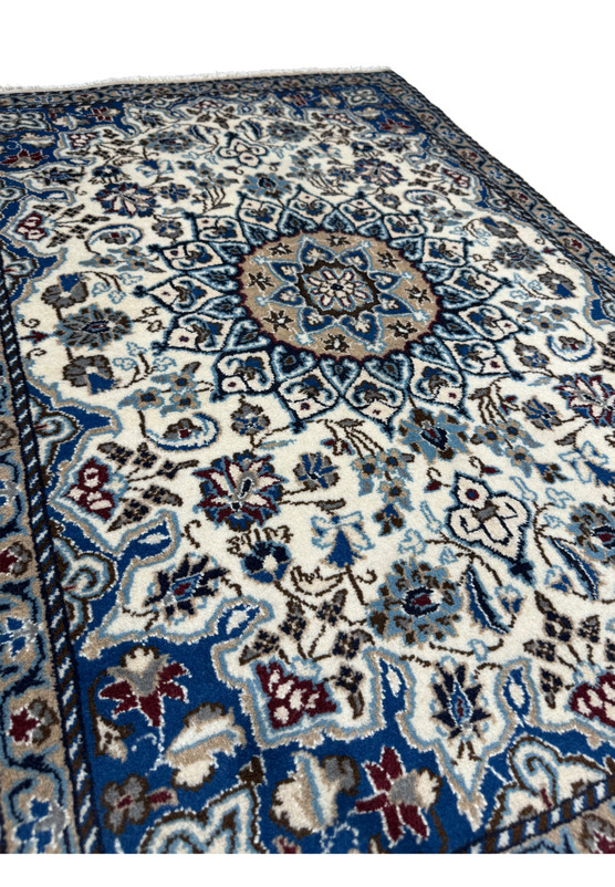 Angled view of authentic 3x4 Persian Nain rug showing full pile and saturated ivory and blue palette