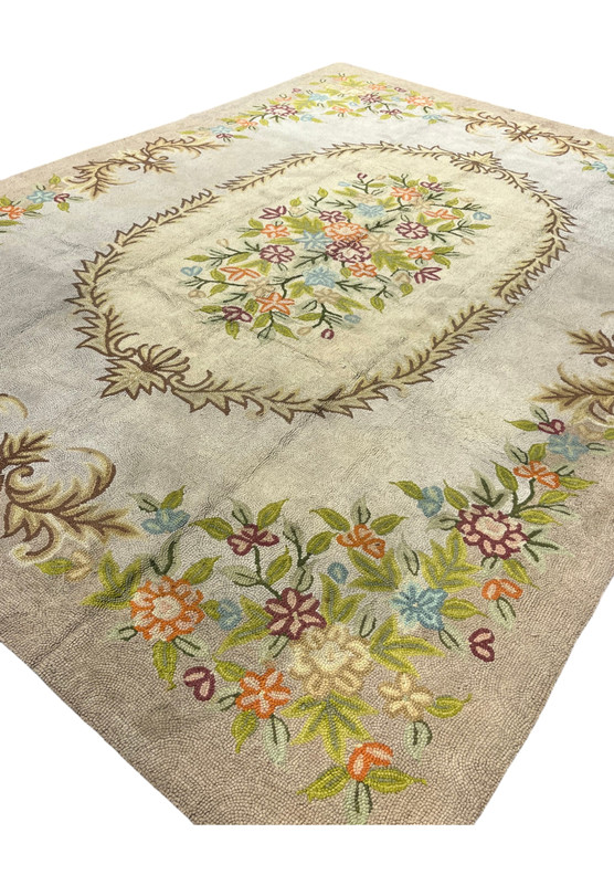 Angled view of the 8 x 11 Indian hooked rug showing its floral medallion and leaf border