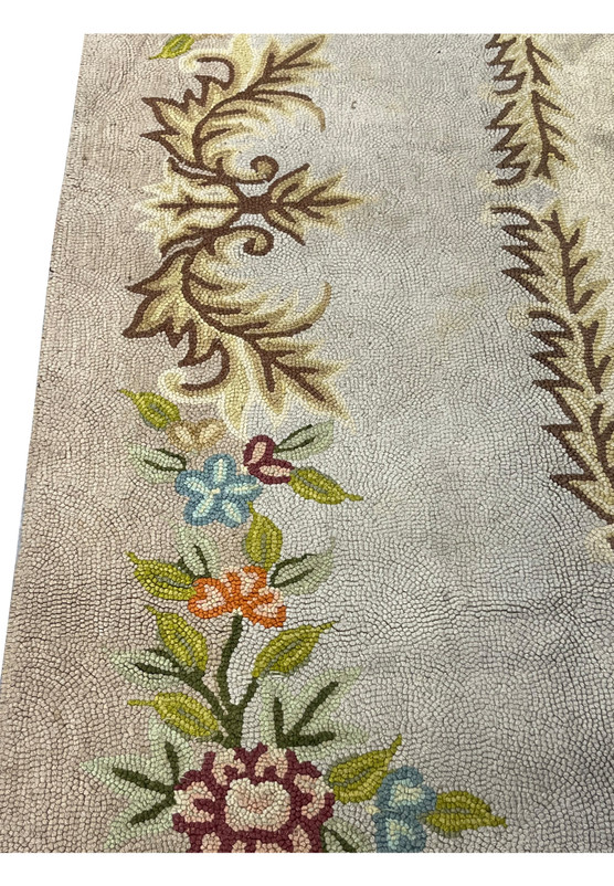 Scrolling acanthus leaf corner and delicate floral spray showing the fine hand hooked wool craftsmanship