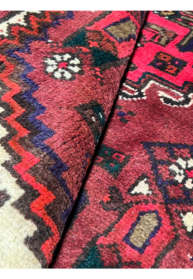 Rolled view of an antique Persian Hamedan rug highlighting thickness, flexible hand-knotted wool construction, and durable village weaving quality