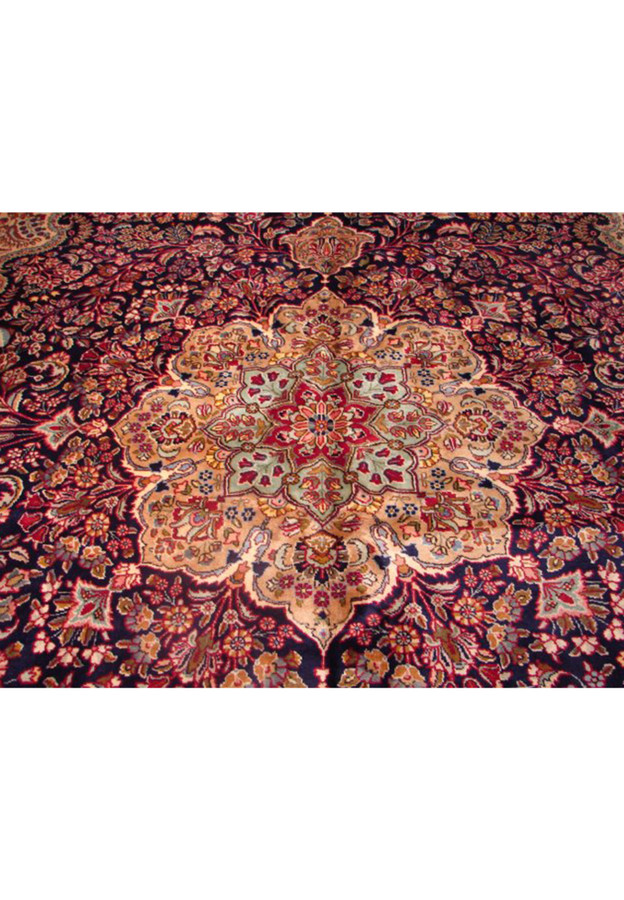 Close-up of the intricate medallion on a Persian Mashad rug featuring navy, crimson, and soft pink detailing
